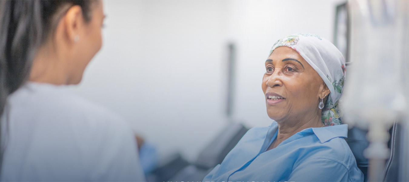 A nurse talking with a cancer patient with head scarf on